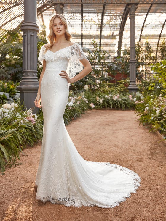 Elegant, with a touch of bohemian goddess, this mermaid gown made of fine lace has a feathery back and collarbone accent, and a long, svelte skirt finished in a wide scalloped edge.  