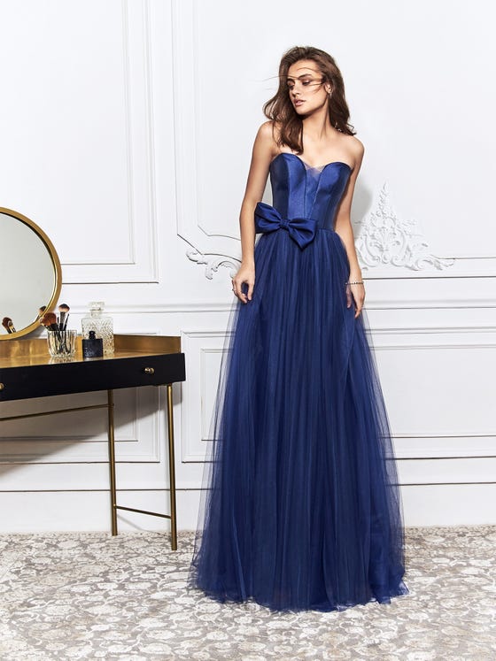 Chic, criss-cross panelling lines the sweetheart, plunge bodice of this navy blue mermaid gown, which features a glossy bust and statement bow at the hip of a long, frothy skirt of soft tulle. 