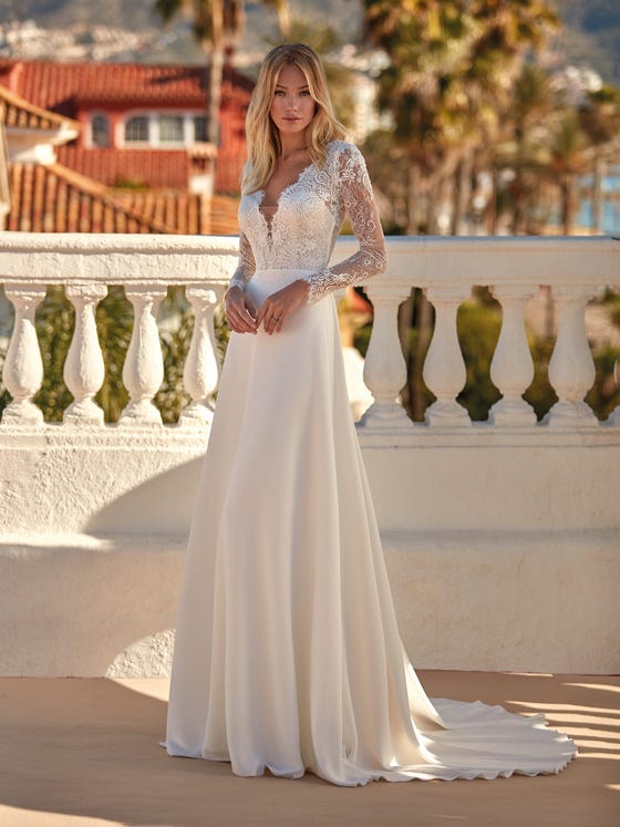 Elegant dress with a crêpe skirt and semi-transparent lace bodice. A fitted, long-sleeve design with a V-neck that offsets the sensuality of the back. 