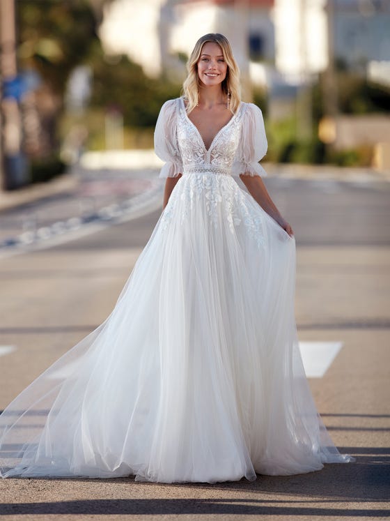 Wonderful tulle dress with a flowy skirt and V-neck. A very special design because it merges the floral lace trend with a romantic style reflected in the removable balloon sleeves. 