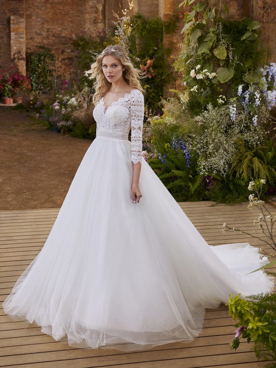 The volume of the tulle on the princess skirt merges with the delicacy of guipure. The play of contrasts enhances the femininity of the silhouette through transparencies, flattering three-quarter sleeves and the provocative V-back. 