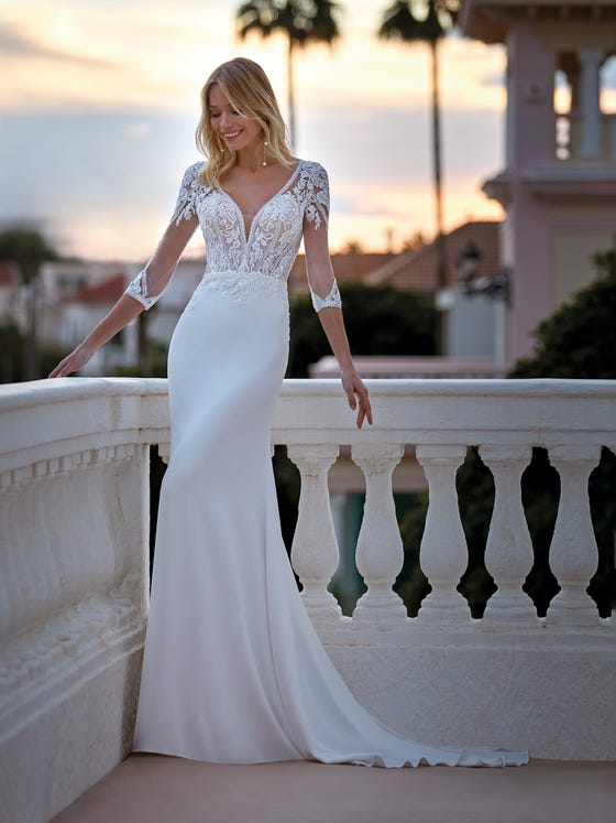 Elegant mermaid dress with a crêpe skirt and tulle  bodice with lace appliques. A play of sensuality and transparencies which are accentuated with the V-neck, the three-quarter sleeves and the keyhole back. 