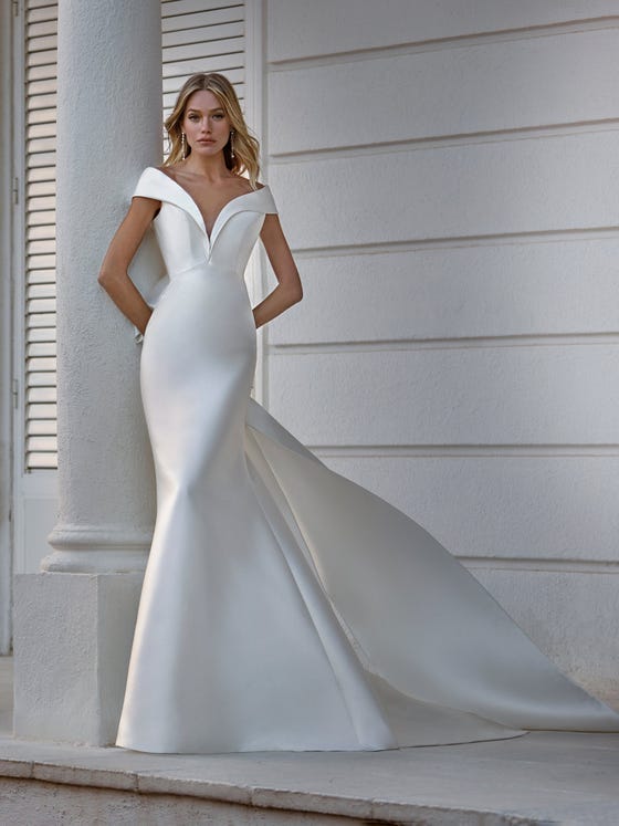 Spectacular Mikado dress with a mermaid silhouette. A very elegant design that combines the sophistication of the fabric with the sensuality of the V-neck and semi-rigid sleeves which drape below the elbow. 