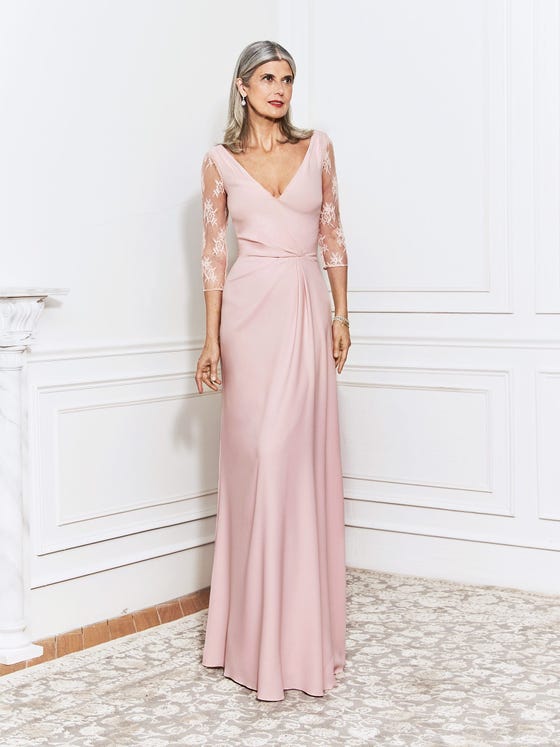Elegant sheath gown in soft pink crepe, featuring a sexy V-neck, Chantilly lace sleeves, and a fitted bodice that gathers delicately at the waistband. 