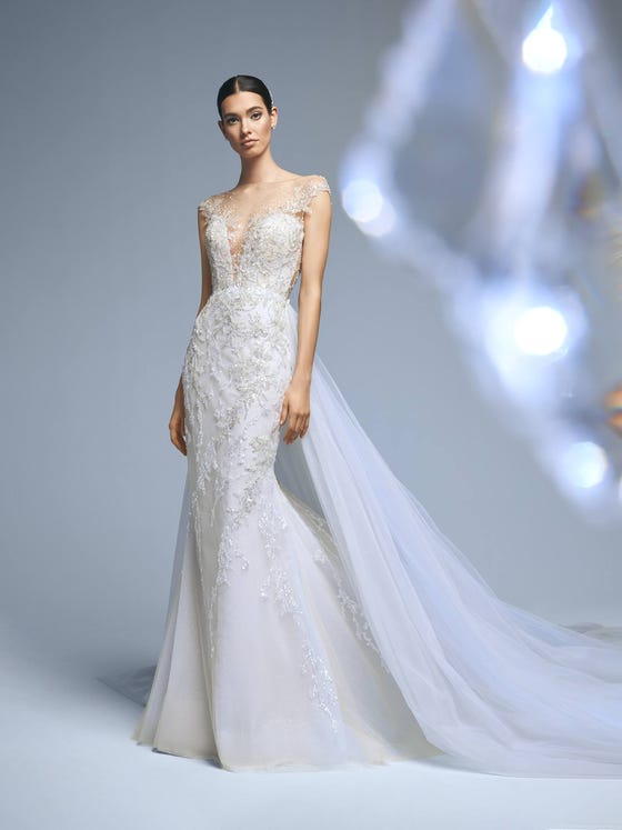 A dazzling mermaid dress in glimmery tulle with beading appliques. A design that enhances your femininity through the transparencies and the tattoo effect of the neckline and back. A very suggestive, elegant look that you can match with the tulle train. 