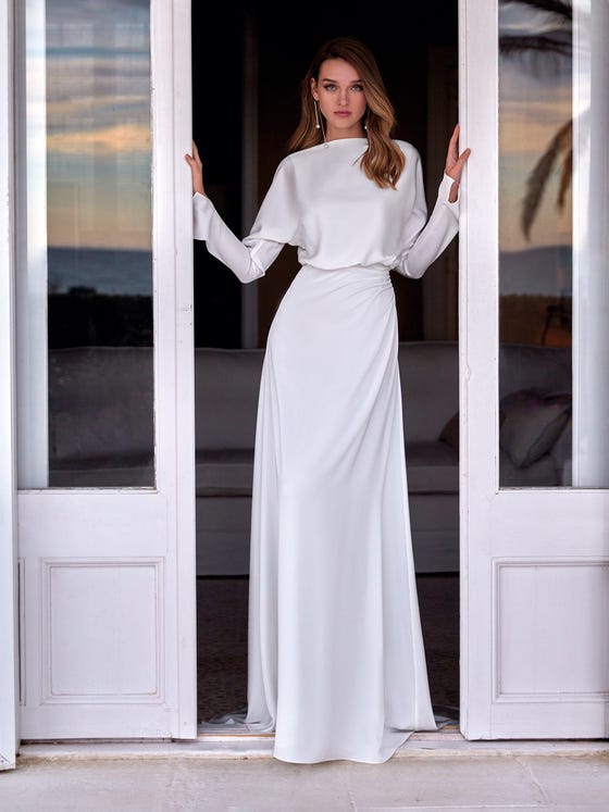 Elegant satin dress with a tube skirt and long dolman sleeves. A trendy design that combines the columned structure of the bottom part with the volume and movement of the bodice with a bateau neckline. The back is decorated with a beaded strap that brings bling to the dress. 