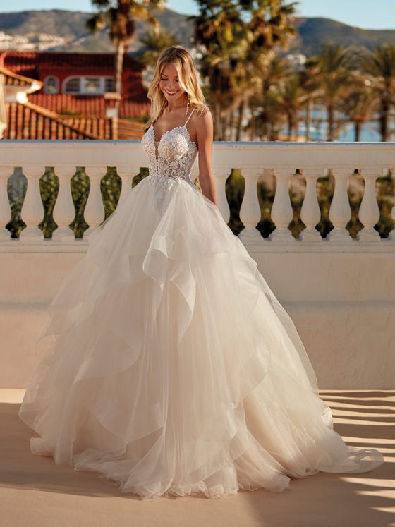 Spectacular princess-style dress with a tulle skirt creating a play of ruffles and volumes. A design that contrasts a romantic lace and beaded bodice that opens in a sensual V-neck with an exposed back crisscrossed by two thin straps. 