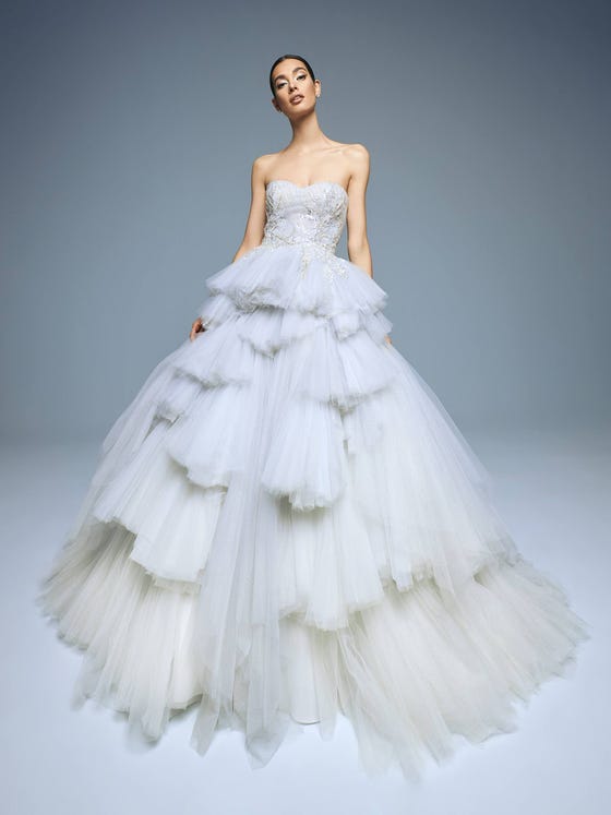 Spectacular. An original dress with plenty of personality that plays with the volume and asymmetrical layers of the glimmery tulle princess skirt, which combines with a draped bodice covered in beaded appliques and floral embroidery that set off the illusion neckline. 