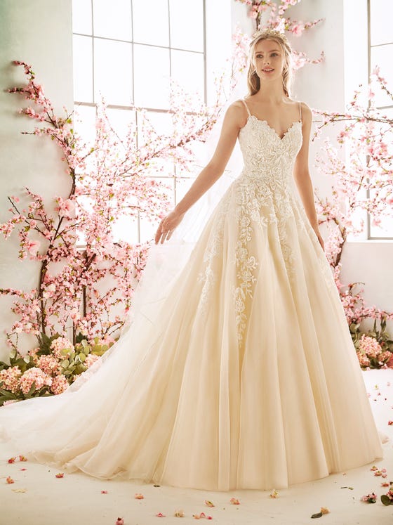 Princess gown in creamy tulle, featuring spaghetti straps and a sweetheart bodice adorned in subtly sequined roses that travel down the skirt in romantic vines. 
