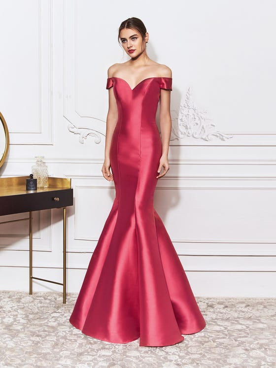 Lustrous mermaid gown in red Mikado, featuring fine, flattering cuts that form a sweetheart bust, a fitted waist, and elegant off-the-shoulder sleeves that wrap around to a chic bow at the back. 
