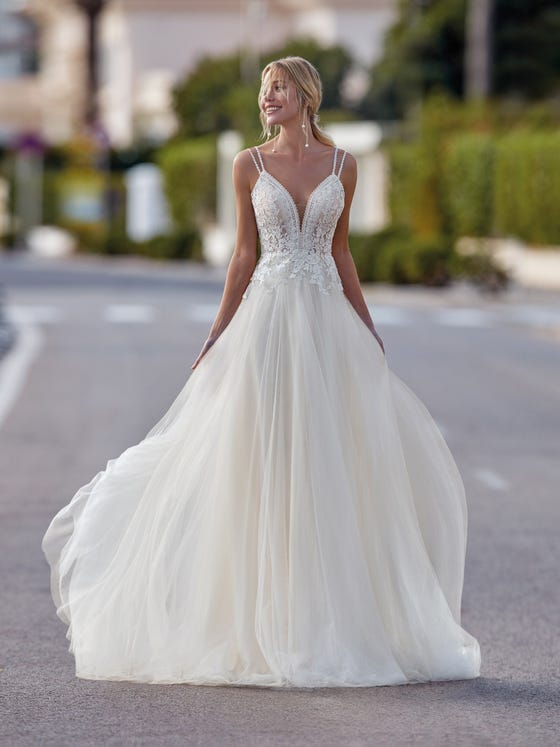 Incredible tulle dress with flowy skirt and fitted bodice decorated with lace appliques and a sensual V-neck. A sleeveless design with thin guipure straps. 