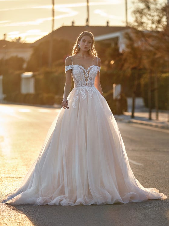 Beading and tulle define this sensational princess-cut dress with a fitted bodice decorated with embroidery and glimmers descending from the waist. A design with off-the-shoulder sleeves and thin beaded straps. 