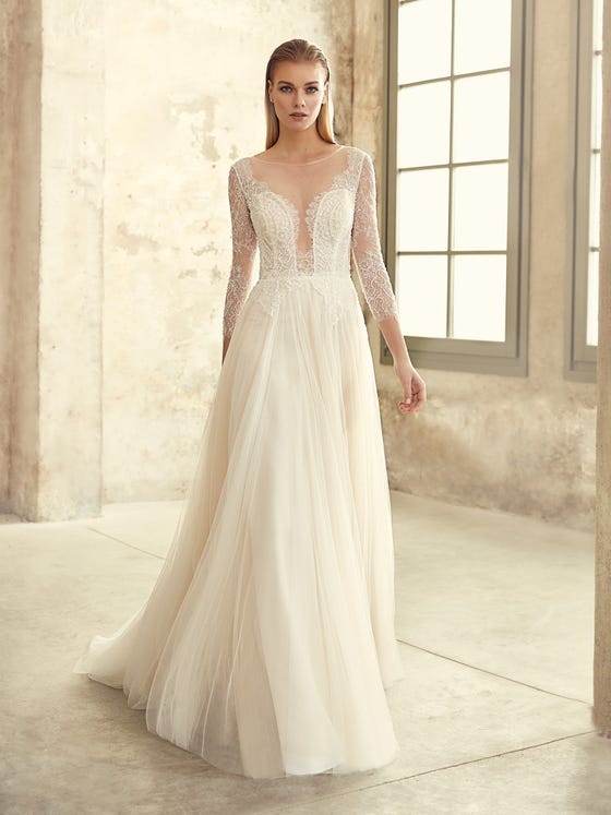This young, romantic evasée-style dress features a softly gathered skirt in layers of gossamer tulle, paired with an exquisite bodice embellished with fine beading. Schoolgirl sleeves contrast with a sensual illusion back and deep V neckline.  