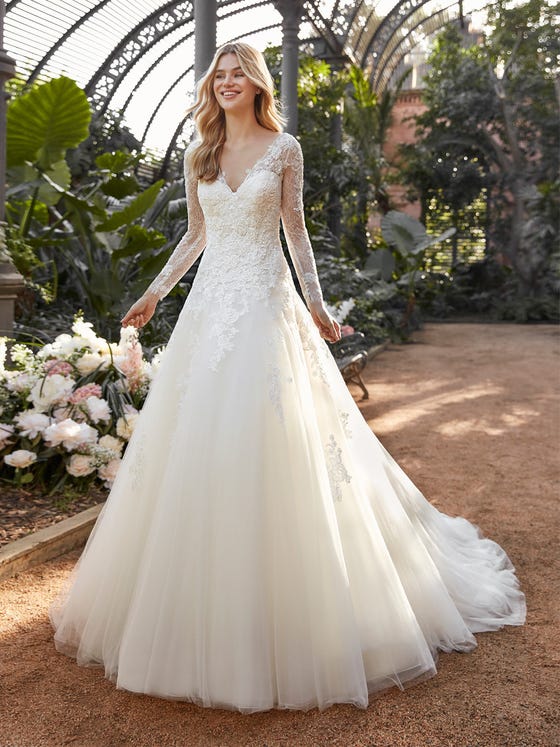 Soft embroidered tulle reaches its full expression on this A-Line wedding dress with a billowing, layered skirt and sumptuous V-neck bodice with long fitted sleeves.  