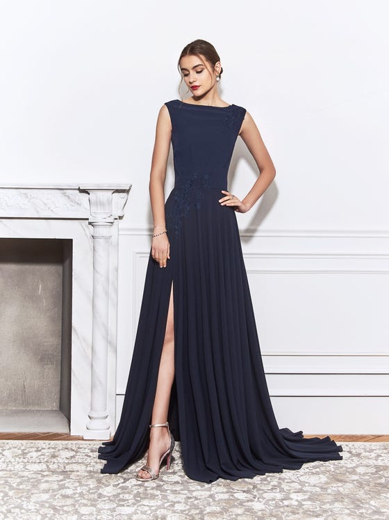 Angled cuts of French, blue lace line the shoulder and waistline of this Georgette sheath gown, designed with cap sleeves, a bateau bodice, and a high slit skirt that complements the low, open V-back. 