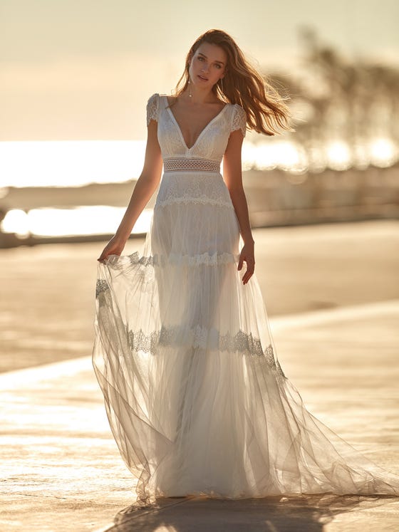 A dress with a very bohemian feel in tulle, lace and guipure. A very romantic design which highlights the silhouette with a beautiful A-line cut and enhances your sensuality with a V-neck front and back and short scalloped sleeves. 