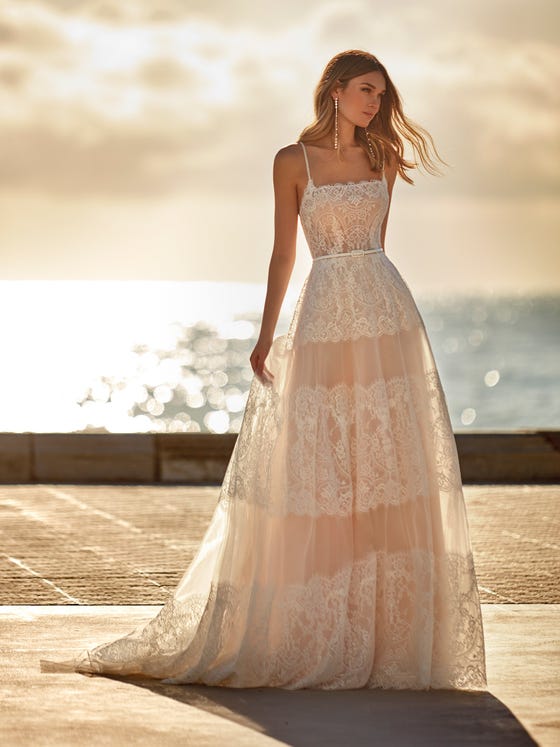 Beautiful romantic tulle dress with a flared skirt decorated with rows of Chantilly which merge with the bodice. A design with a flattering square neckline with sequins and an exposed back with thin crossover straps. 