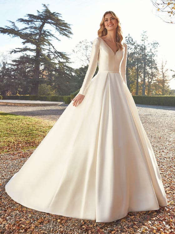 Glossy Mikado creates a formal gown reminiscent of classic French couture with a full volume skirt and tailored sleeves and bodice. With gentle lapels framing a plunge back and an extra long sweep of row buttons.  