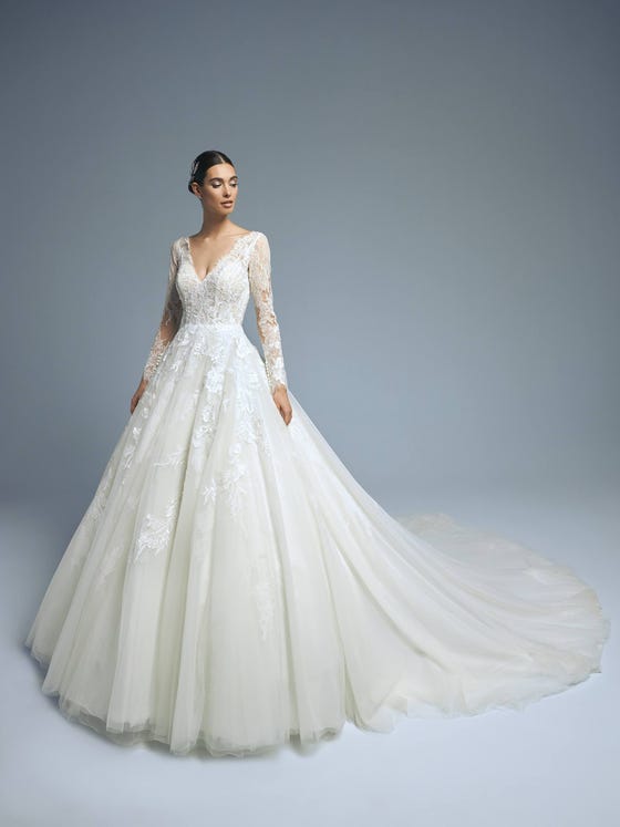 A princess dress in tulle with a long train and a spectacular illusion back. A perfect combination of femininity and sensuality. The long semitransparent sleeves and V-neck enhance a highly sophisticated silhouette. 