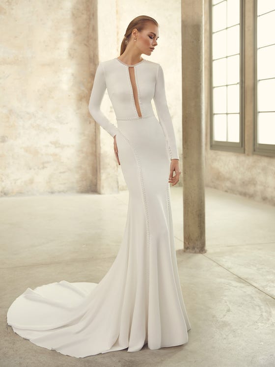 A supremely elegant and ageless gown crafted in liquid crepe that skims and shapes the body. With long fitted sleeves and a keyhole back embellished in subtle rhinestones and row buttons.   