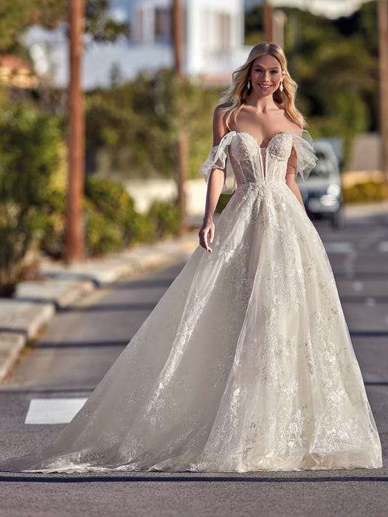 Spectacular tulle dress totally enveloped in floral lace appliques. A design that highlights the femininity of the silhouette with a sweetheart neckline and corset-style bodice with removable tulle sleeves. 