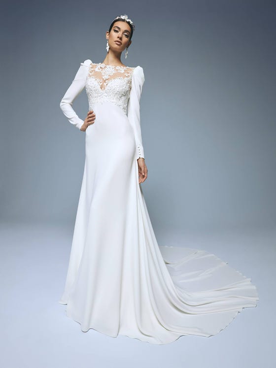 Fabulous crepe dress with a flared cut, train and long puffed sleeves. Its unique sweetheart neckline in tulle and lace, with beading appliques, creates a very sensual tattoo look. 