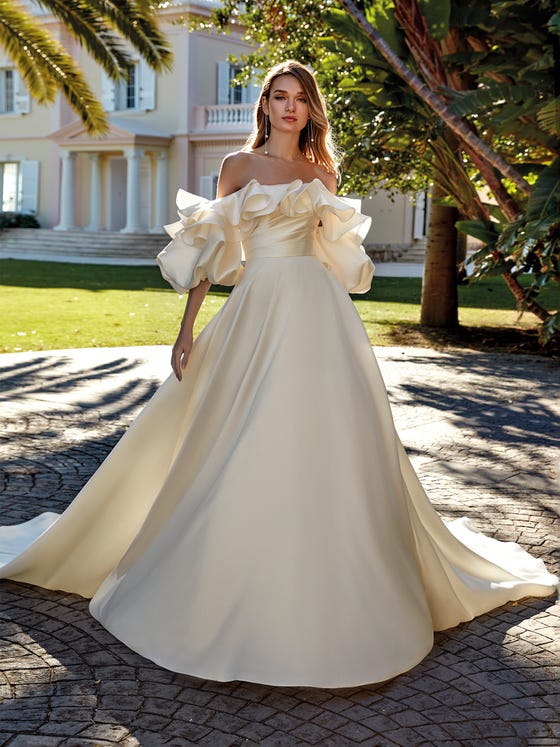 Elegant golden Mikado dress with a pleated bodice and original play of ruffles and volumes that merge with the neckline with oversize, draped sleeves. 