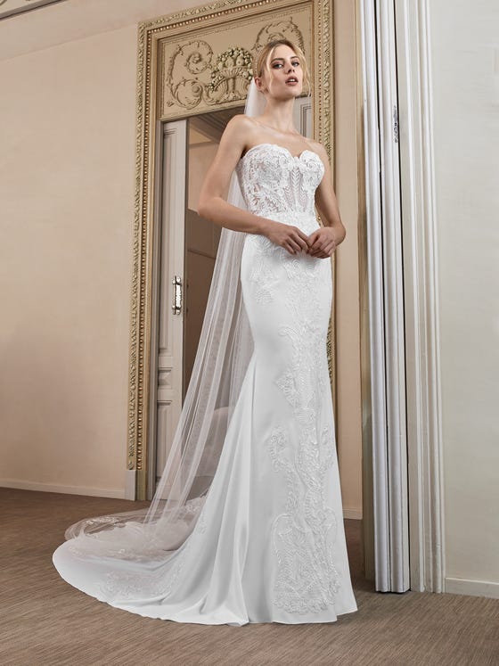 Strapless mermaid gown featuring semi-illusion, sweetheart bodice of leafy, patterned lace that travel down the skirt and finish in a sleek skirt of white crepe. 