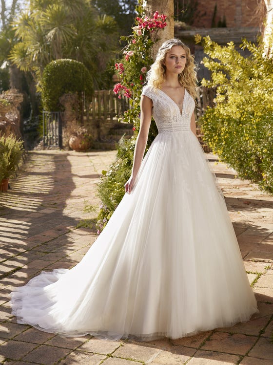 Guipure and tulle, two incredible fabrics to give shape to a wonderful princess wedding dress. A dress with classical lines, short sleeves and a V-neck that breaks with tradition with its trendy keyhole back. 
