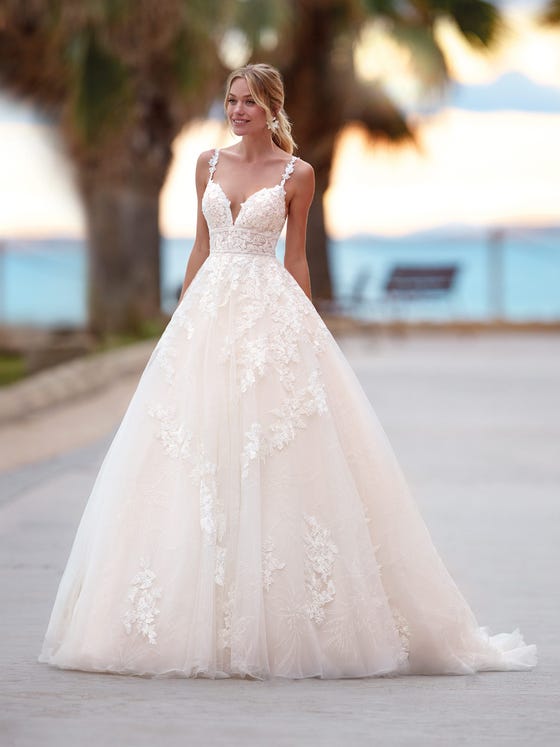 Romantic princess-style dress with V-neck and thin straps. A tulle design decorated with glimmering floral motifs and lace and beading appliques that cascade down from the bodice. 