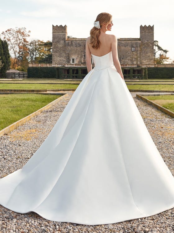 Simple, chic and romantic, this princess style gown in glossy Mikado has a deep sweetheart neckline and cutaway back, and is perfect for customizing with belts ad bows.  