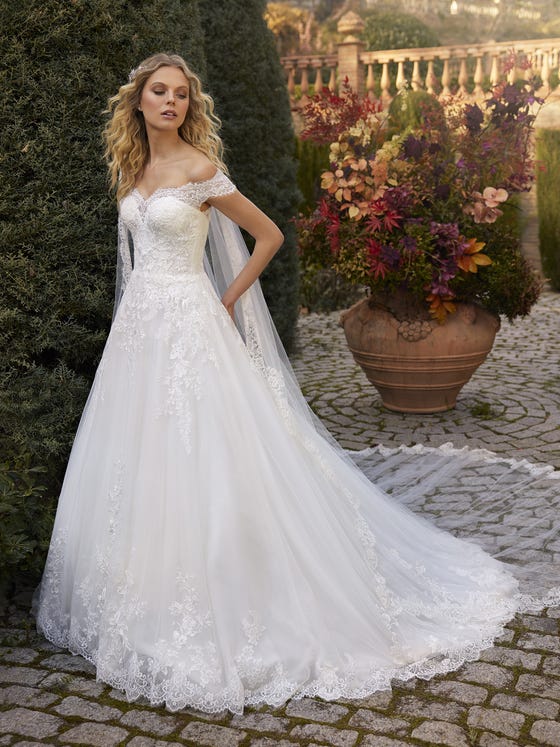 A beautiful princess lace dress with flowers running around the bodice and skirt creates a highly feminine silhouette accentuated by the flattering off-the-shoulder neckline. 