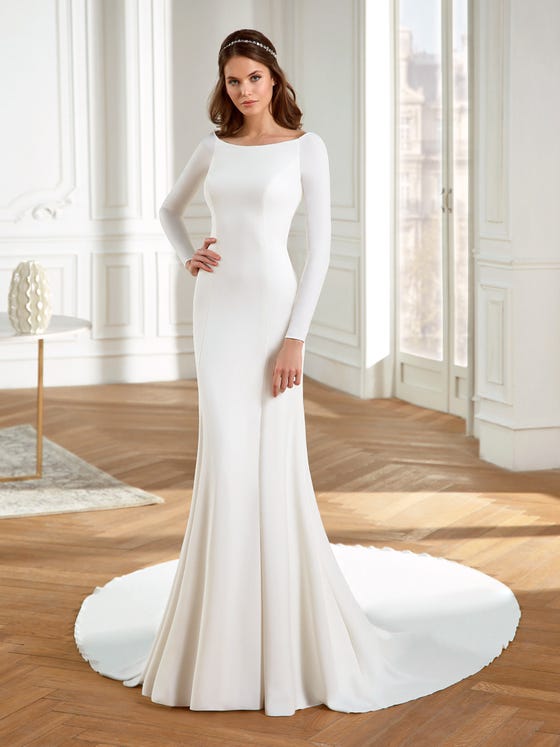 Minimalist mermaid gown in creamy crepe, designed with long sleeves, a wide-bateau neckline, and breathatking cuts that hug the hips and flatter the figure. 