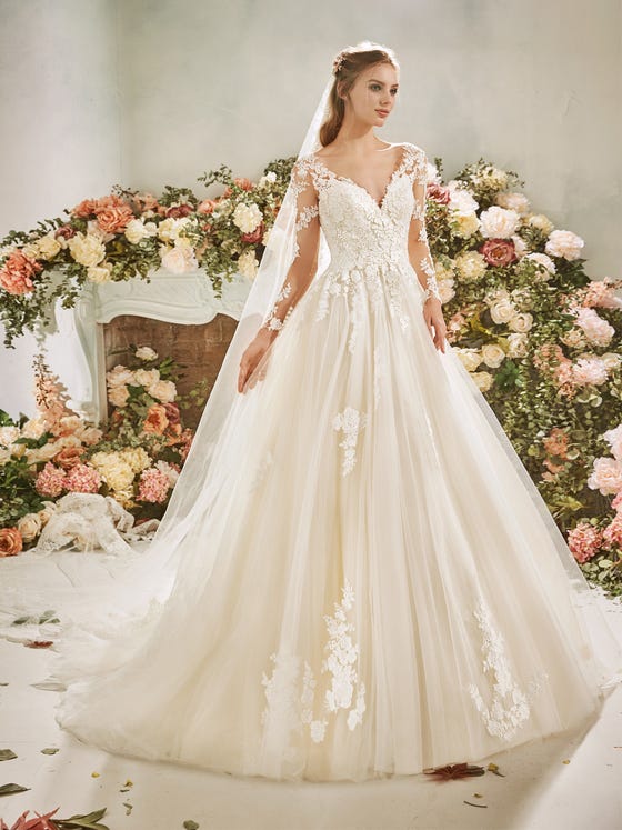 Classic princesss gown with long, tattoo sleeves and an elegant, V-neck bodice coated with cuts of French lace flowers that trickle down the waistband and finish at the edges of a long, layered skirt in soft tulle. 