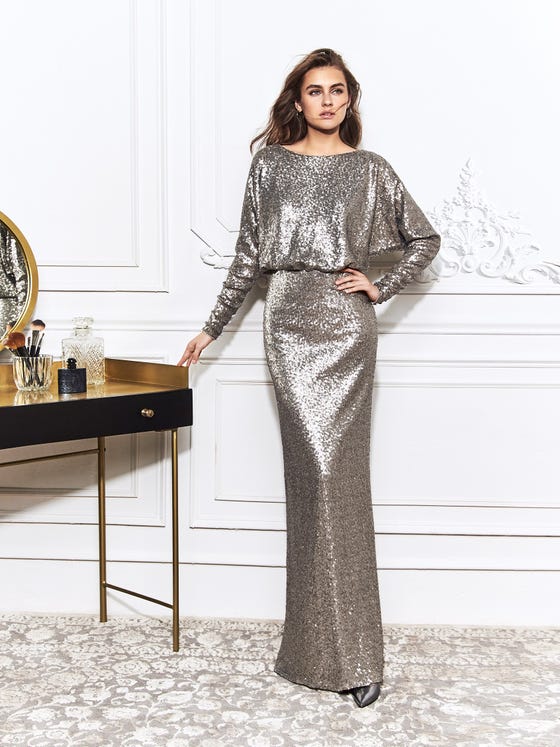 Stunning gown that glitters in all-over, golden sequins, crafted with an oversized bishop bodice, long fitted sleeves, and an angular keyhole back for a subtle, sexy finish. 